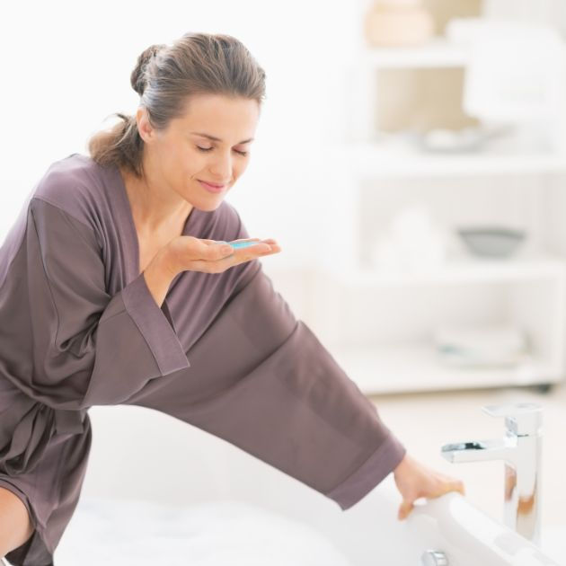 Woman shown smelling a nice shampoo and looking relaxed and happy due to the effects of the fragrance