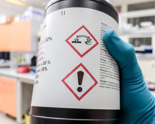 Bottle of chemicals showing warning labels on cautions for handling potential dangerous chemicals when cleaning your grease trap.